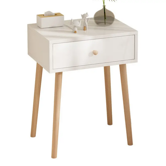 White bedside table with wooden legs, single drawer, tissue box, decorative cat figurines, and glass vase